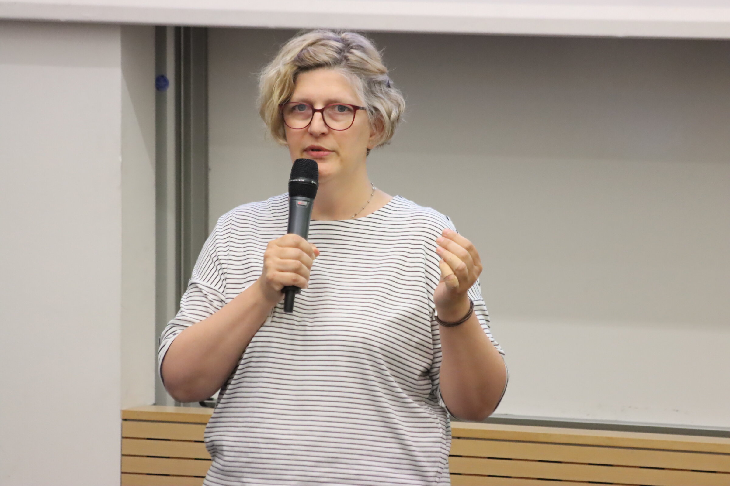 Melanie Ebener steht im H&ouml;rsaal, ein Mikrofon in der Hand.