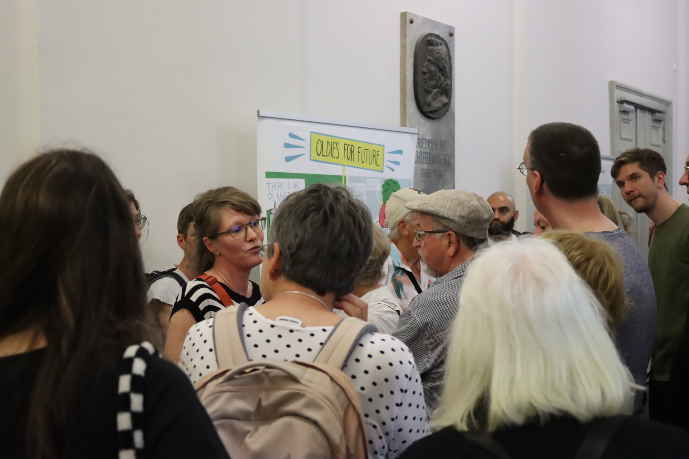 Gr&ouml;&szlig;ere Anzahl von Menschen steht vor der noch verschlossenen T&uuml;r des H&ouml;rsaals und wartet.